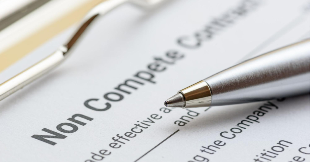 A silver ballpoint pen lays on top of a non-compete contract.