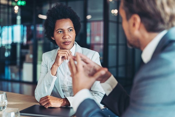 Middle-aged businesswoman listening attentively while in conversation with a male colleague.